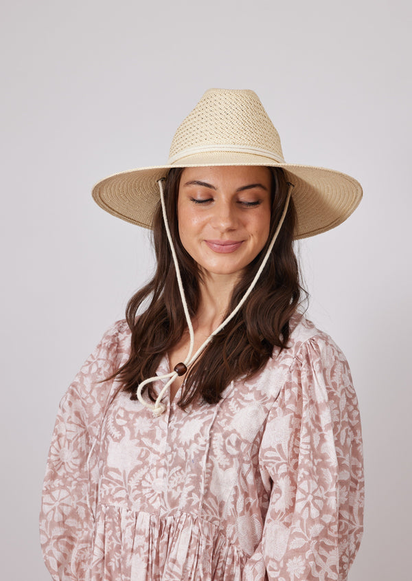 Model wearing surfer style sun hat and floral sundress