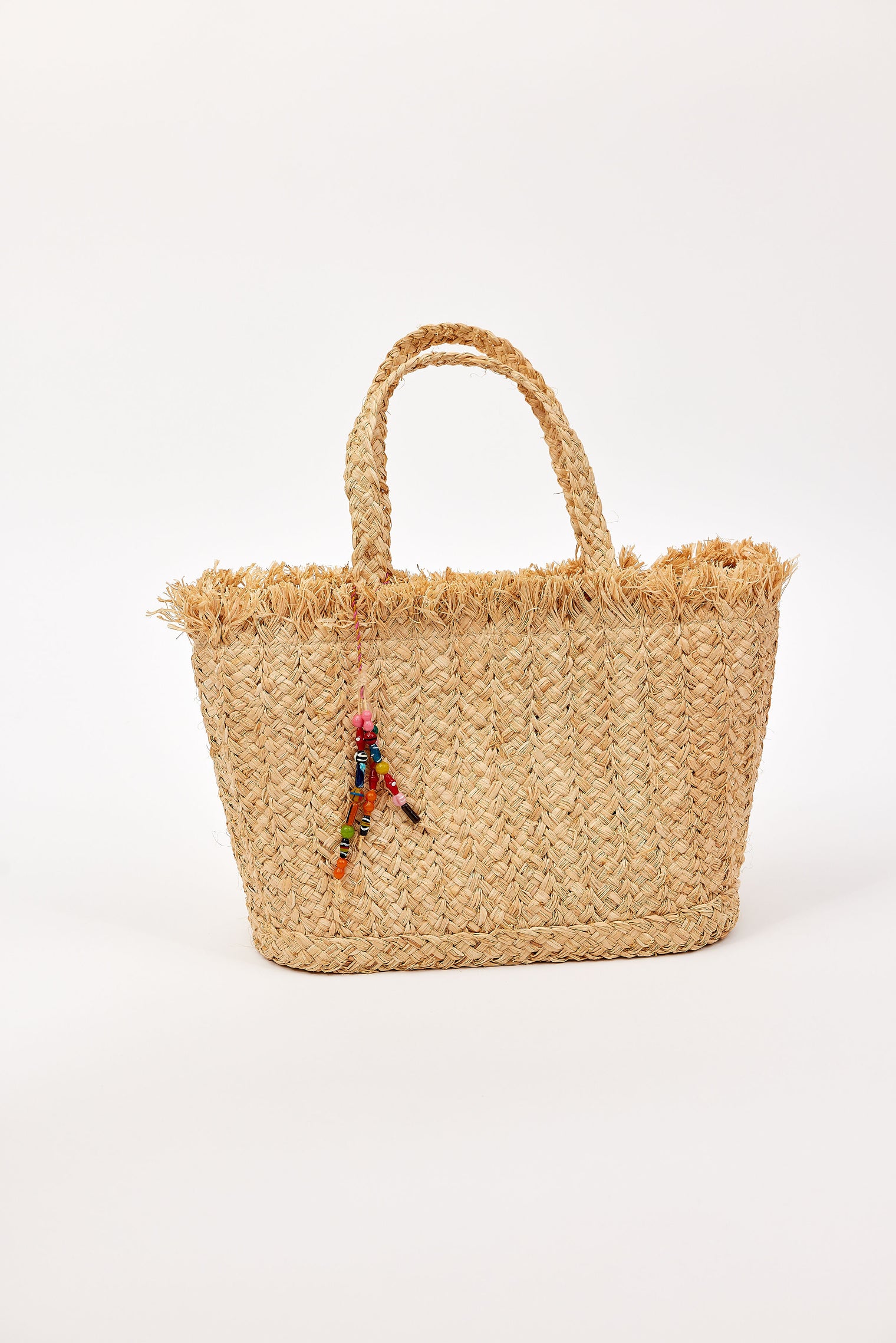 Woven straw bag with colorful charm on a white background