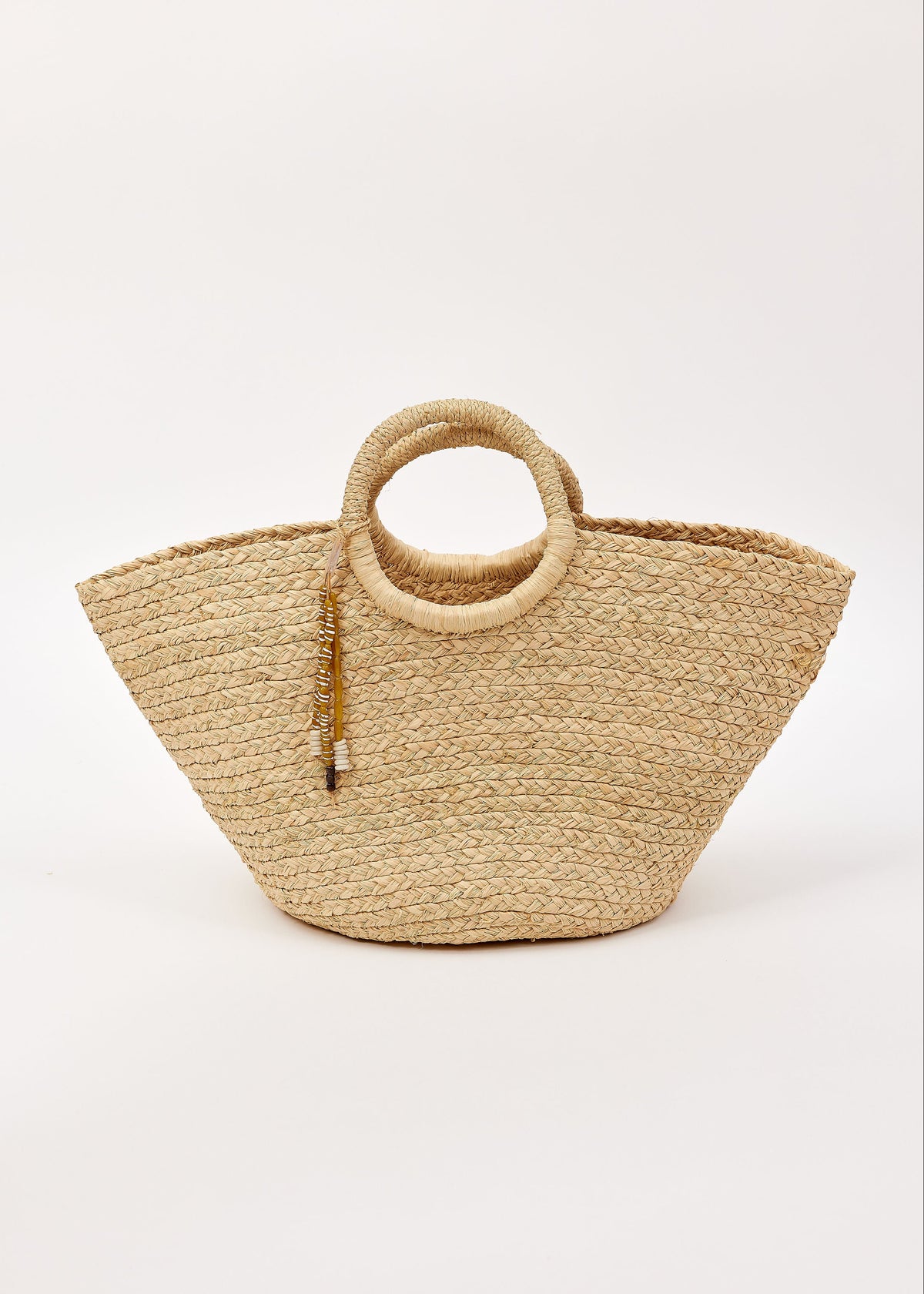 Woven straw bag with circular handles and tassel detail on a white background
