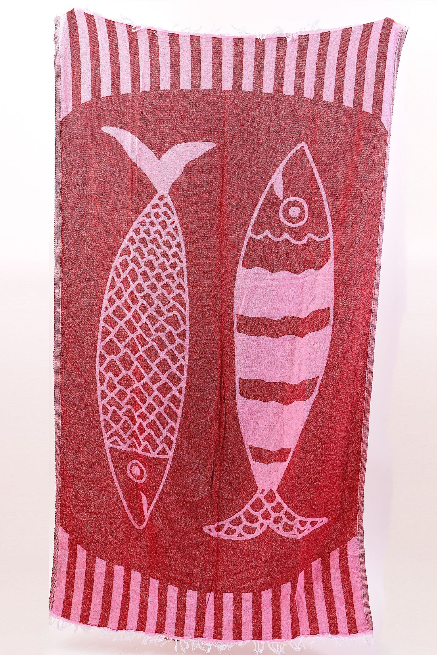 Red towel with white fish design and striped border on a white background