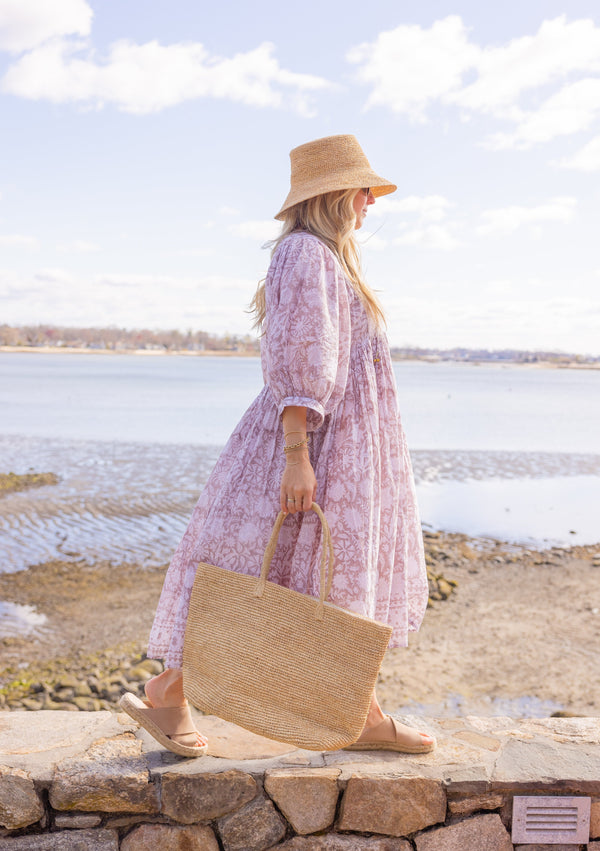 Model walking with large straw beach tote