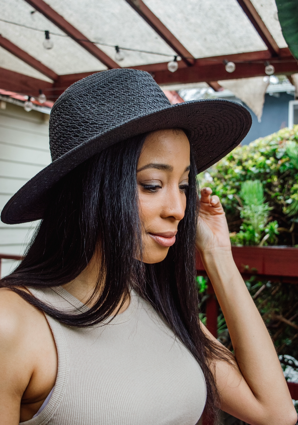 Model holding brim of black sun hat