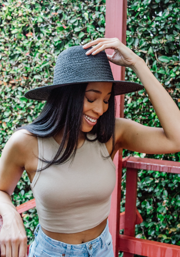 Model smiling while holding crown of black sun hat