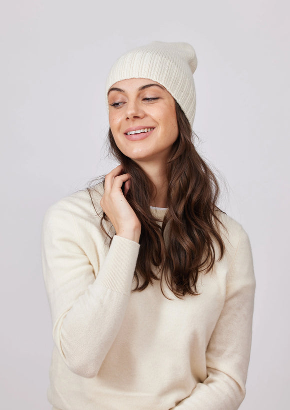 Woman wearing white cashmere beanie hat and white cashmere sweater.