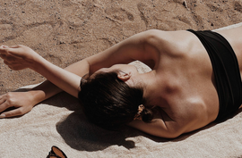 Woman laying on the towel on the sandy beach.