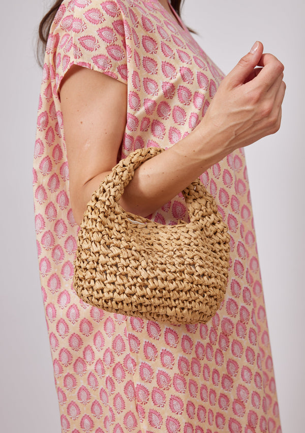 Model holding small tan slouch bag