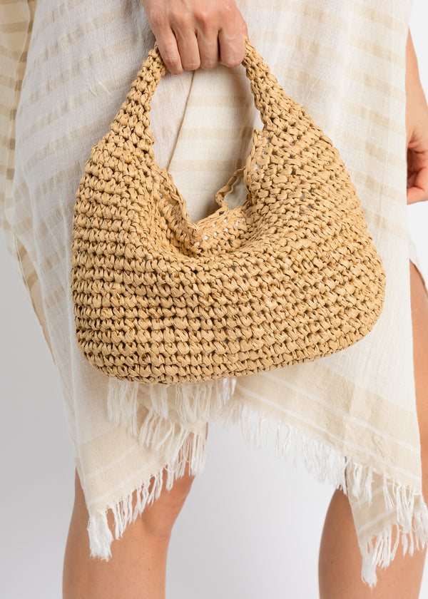 Model holding tan straw slouch bag