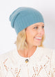Close up of marine blue cashmere slouchy beanie on model wearing ivory sweater