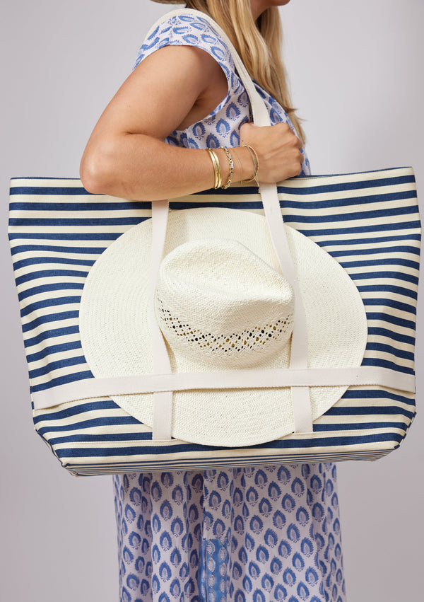 Model holding white and navy striped tote over shoulder