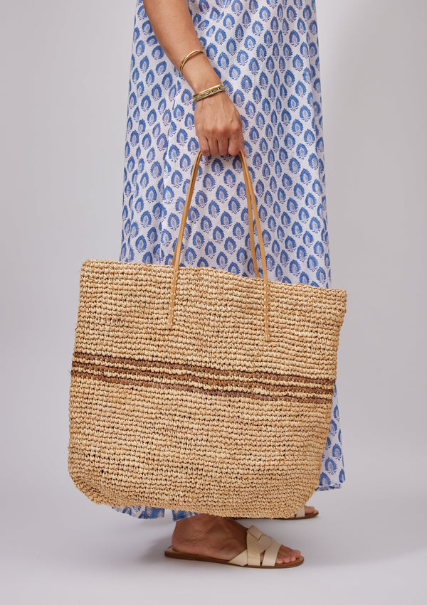 Model holding straw bag with brown stripes