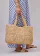 Model holding a straw tote and wearing a blue kaftan