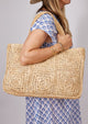 Model holding a straw tote over her shoulder