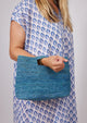Model holding blue straw bag and wearing blue kaftan