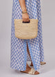 Model holding tan straw bag