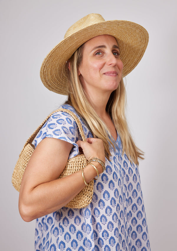 Model wearing small straw bag on shoulder
