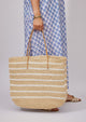 Model holding straw tote with white stripes