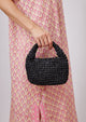 Model holding small black straw slouchy bag