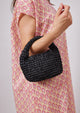 Model holding black small slouch bag and wearing pink kaftan