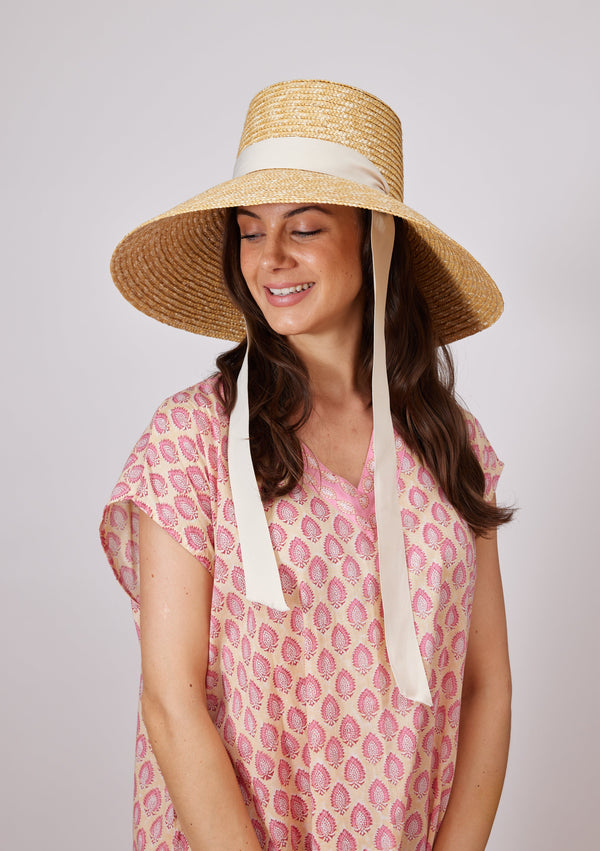 Large brimmed sun hat on model with ivory ribbon tie looking down