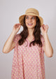 Natural straw bucket hat with brown trim on model holding brim