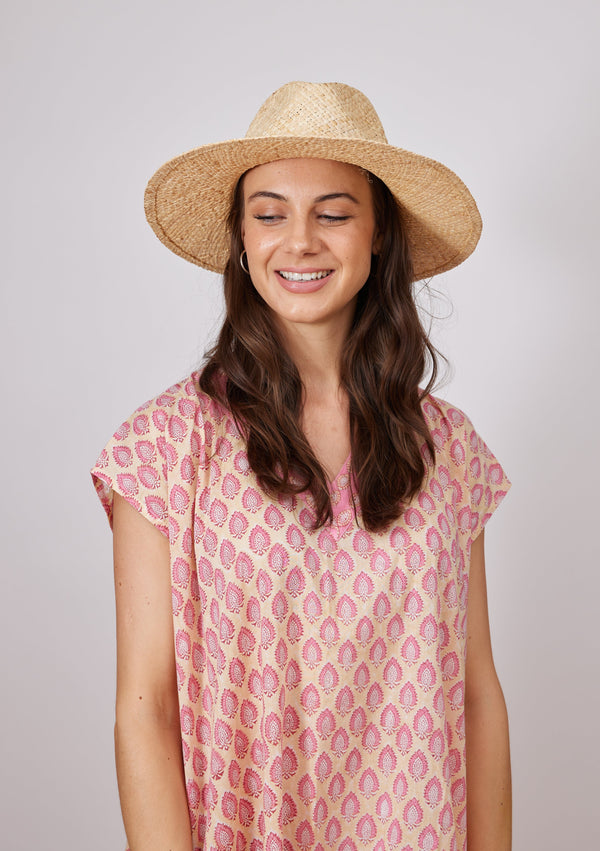 Model wearing woven sun hat and pink kaftan