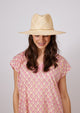 Model wearing pink kaftan and woven straw hat with chainlink detail