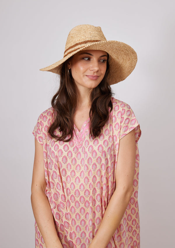 Model wearing pink kaftan and sun hat with double brown stripe detail
