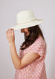 Model holding brim of white sun hat with tan tie detail