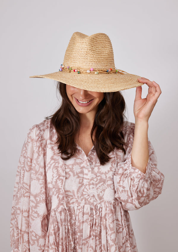 Model holding brim of straw hat with colorful bead trim