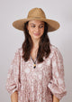 Model wearing straw sun hat with black trim and chinstrap looking to her left
