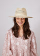 Model wearing striped sun hat and tan floral kaftan