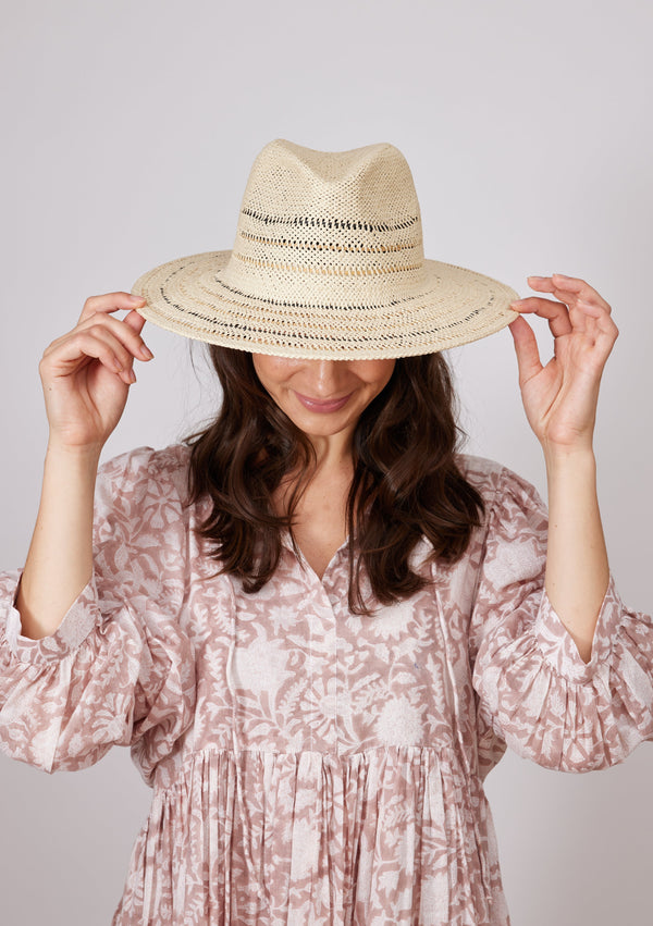 Model wearing striped sun hat and holding brim