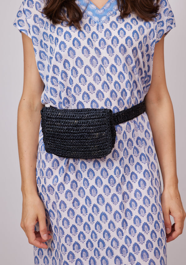 Model wearing blue kaftan and black straw belt bag around waist