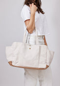 Model holding white tote with pockets on arm