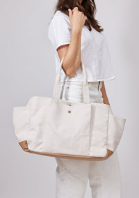 Model holding white tote with pockets on arm