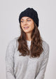 Model wearing grey sweater and black cable knit cuffed beanie