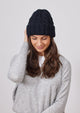 Model wearing black cable knit cuffed beanie and holding head