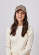 Model wearing ivory and brown small plaid cap and ivory sweater