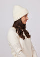 Model looking to her left and wearing ivory knit cuffed beanie