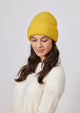 Yellow cuffed knit beanie with ivory beanie looking down