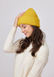 Yellow knit cuffed beanie on model in ivory sweater