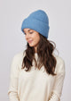 Model wearing denim blue knit beanie and looking down to her right