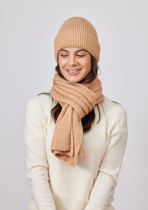 Model wearing camel brown ribbed knit beanie, scarf and ivory sweater
