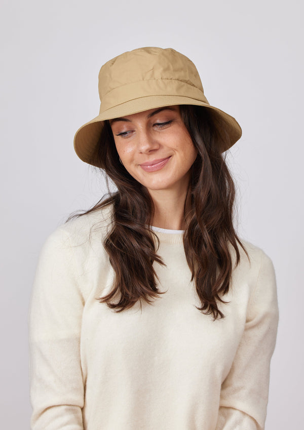 Model wearing a camel brown water resistant bucket hat