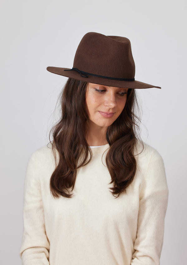 Model looking down and wearing a brown wool felt brimmed hat