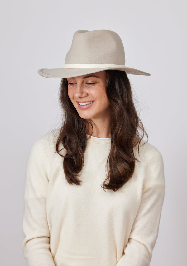 Smiling model wearing beige wool felt brimmed hat with ivory trim