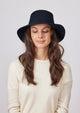 Model wearing black velour brimmed hat and ivory sweater