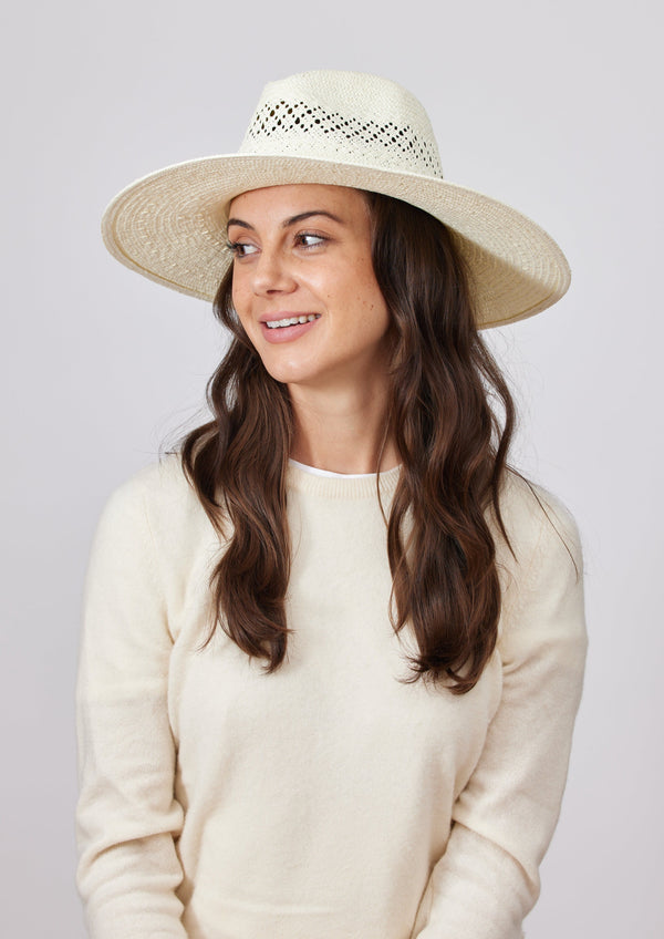 Model wearing white perforated sun hat and white sweater