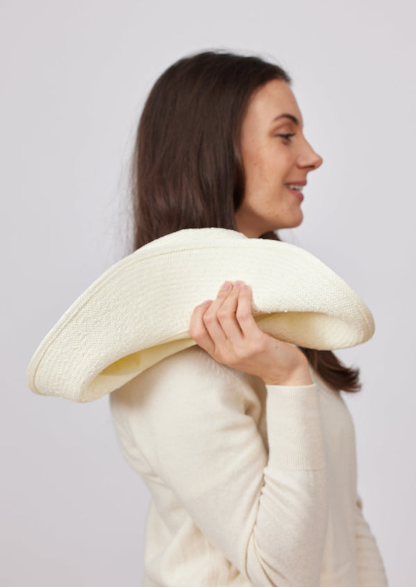 Model folding white sun hat at her shoulder