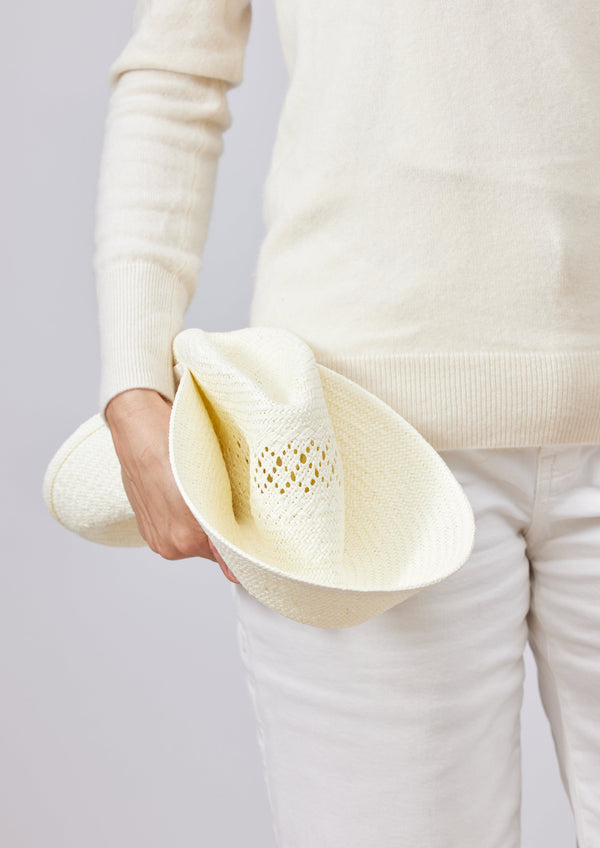 Model folding white sun hat to show that it's packable 